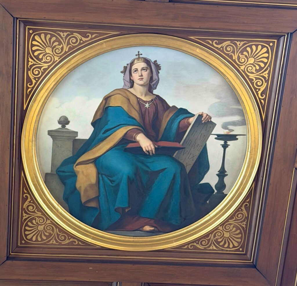 Frau mit blauem Gewand und Schrifttafel, Buch und Kreuz auf dem Haarreif
