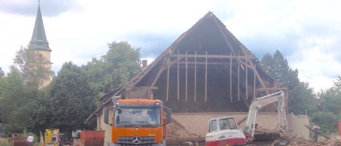 Der alte Kunze-Hof zum Teil abgebrochen mit Bagger davor. Im Hintergrund sieht man den Kirchturm